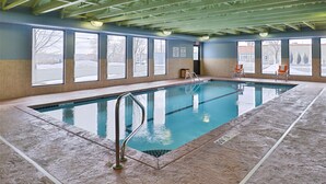 An indoor swimming pool with clear windows, a tiled floor, and a metal ladder. - Holiday Inn Express Rochester - University Area by IHG (Rochester)