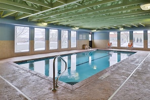 An indoor swimming pool with clear windows, a tiled floor, and a metal ladder. - Holiday Inn Express Rochester - University Area by IHG (Rochester)
