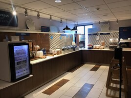 Un área de desayuno con un menú digital, una sección de cereales y una panadería.