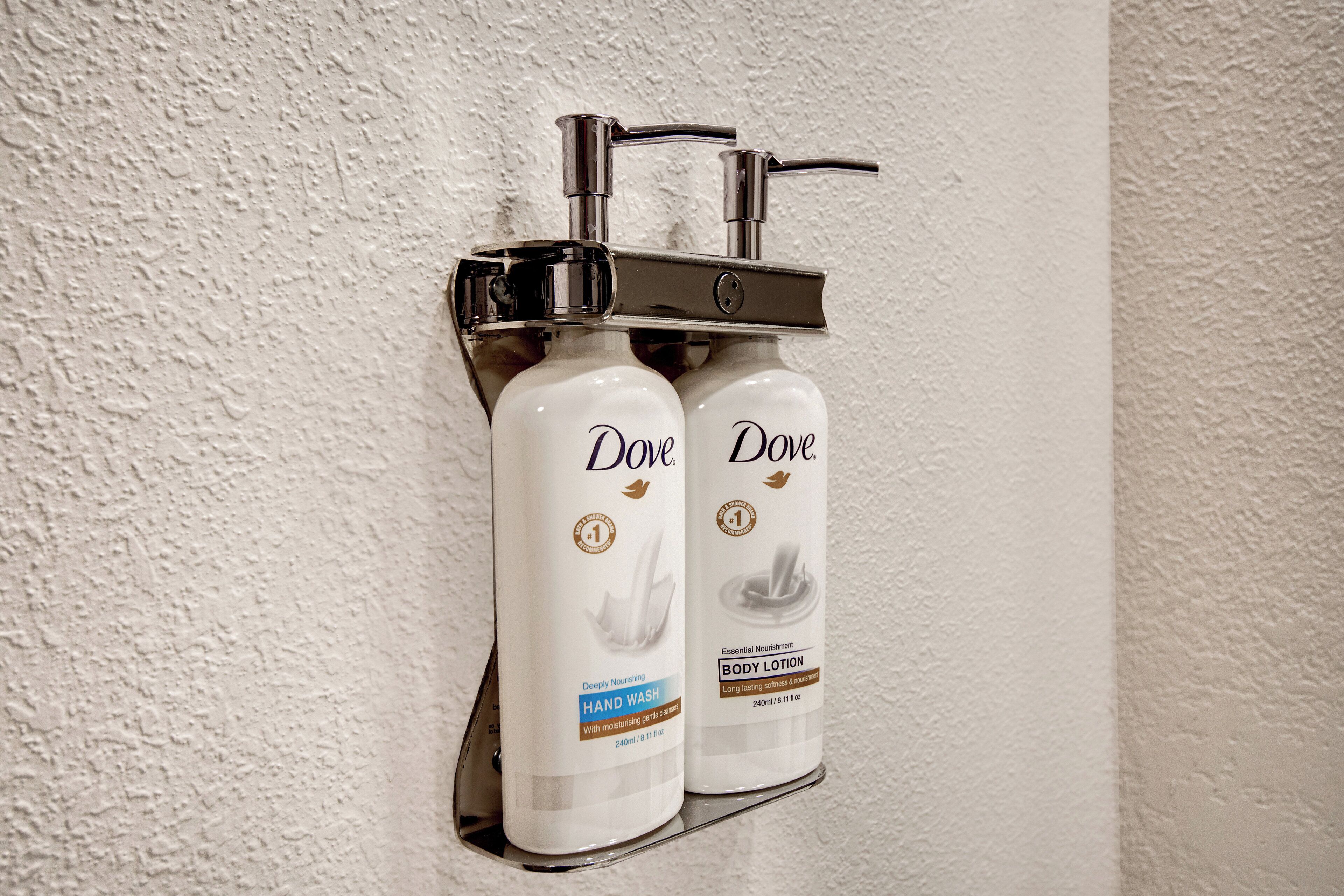 Two Dove hand wash bottles mounted on a wall.