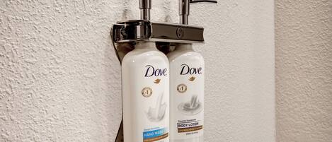 Two Dove hand wash bottles mounted on a wall.