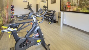 Un gimnasio con bicicletas estáticas, cintas de correr y una variedad de pesas.