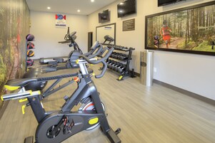A gym with stationary bikes, treadmills, and a variety of weights.