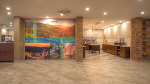 Zona de recepción con un mural grande, una mesa de recepción y un mostrador con detalles de pared de piedra.