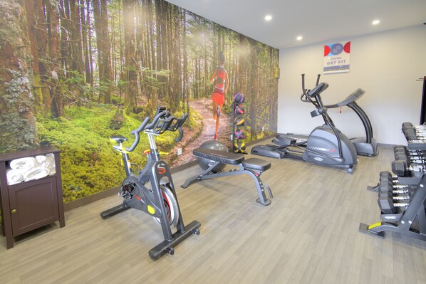 Un gimnasio con bicicletas estáticas, cintas de correr y máquinas de pesas.