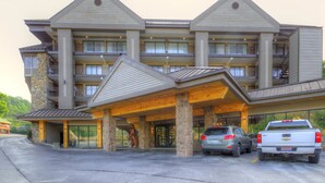 Un hotel de varios pisos con fachada de piedra, balcones y una zona de entrada cubierta.