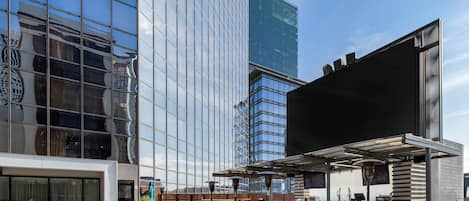 Un patio al aire libre con mobiliario de mimbre y una zona de bar con una pantalla grande.