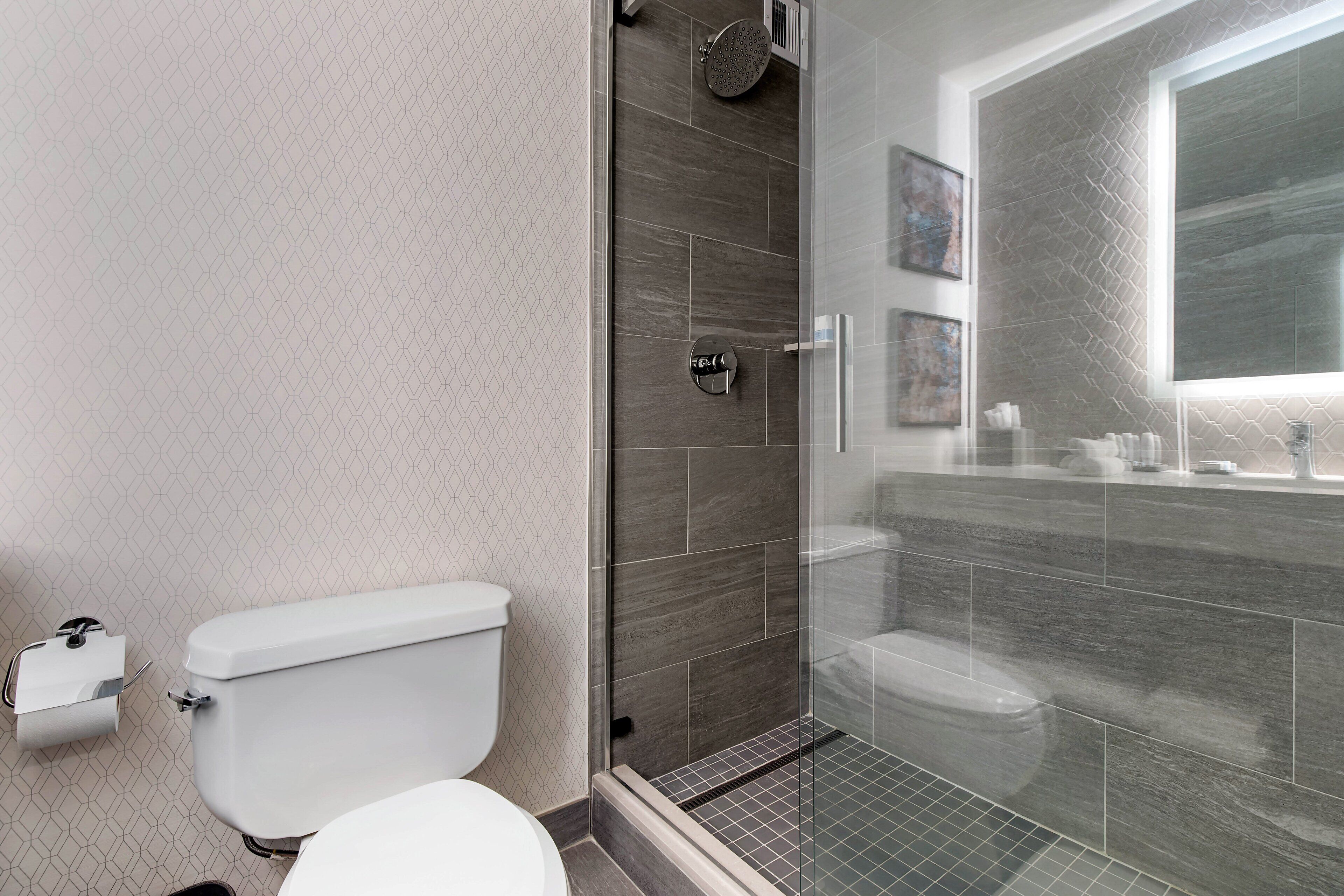 Une salle de bain moderne avec une douche à parois de verre, des toilettes et un lavabo.