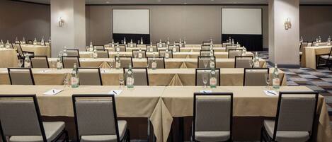 A conference room with multiple tables, each set with chairs, water bottles, and glasses.