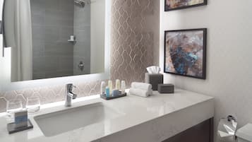 A modern bathroom with a large mirror, a sink, and two framed abstract paintings.