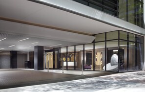 A modern building entrance with a glass facade, a reception area, and a large clock. - Omni Charlotte Hotel (Charlotte)