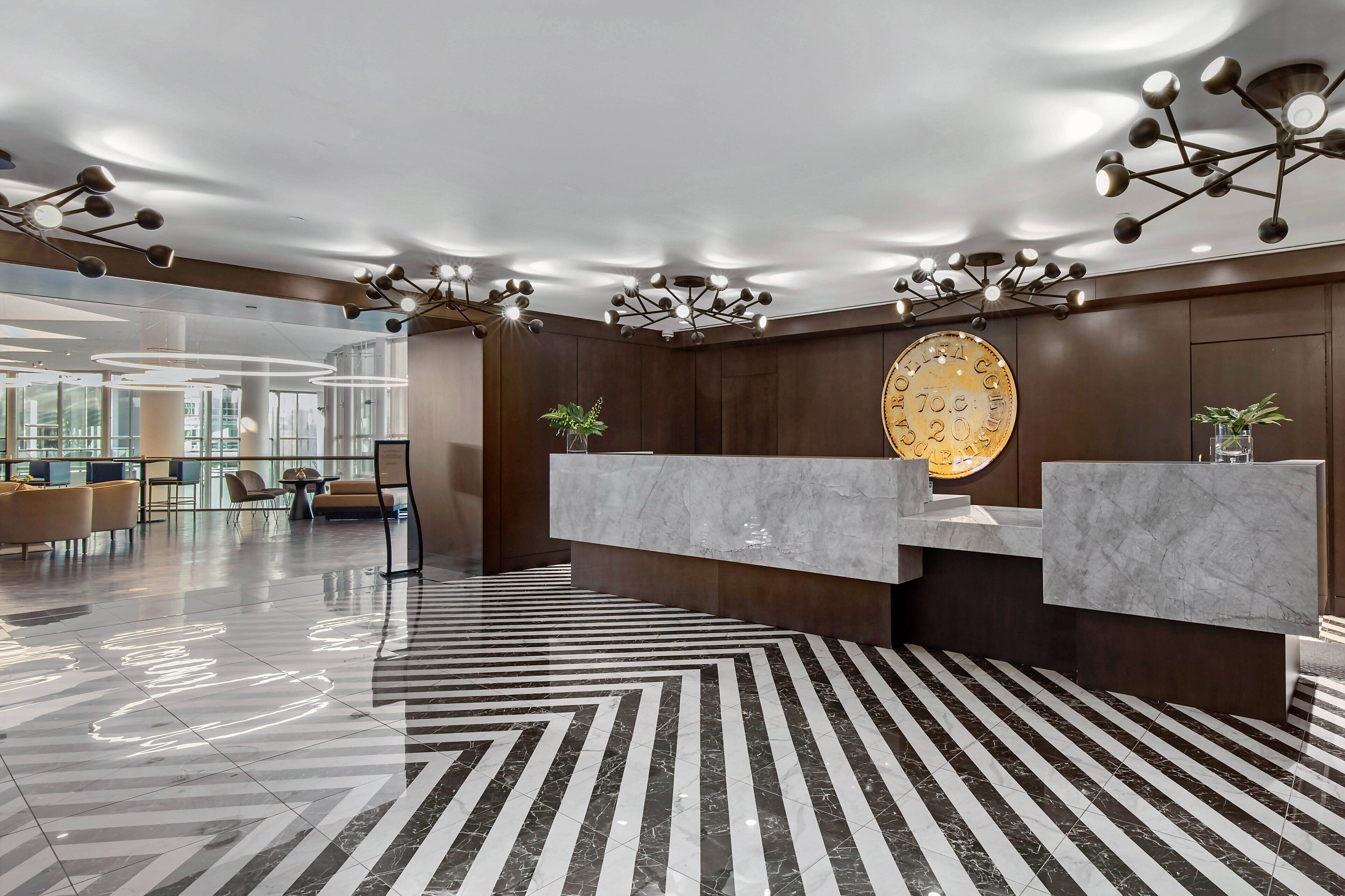 A modern reception area with marble counters, a large wall clock, and a geometric patterned floor.