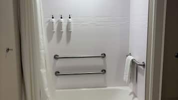 Un baño moderno con bañera hidromasaje, paredes de azulejos blancos y cortina de ducha.