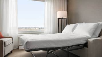 Ein Hotelzimmer mit Bett, Stuhl, Lampe und Blick auf die Stadt.