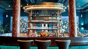A bar area with a circular bar counter, multiple shelves of bottles, and a decorative wall. - The Grand Brighton (Brighton)