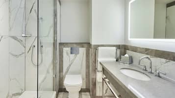 A modern bathroom with a glass-enclosed shower, a toilet, and a vanity with a sink.