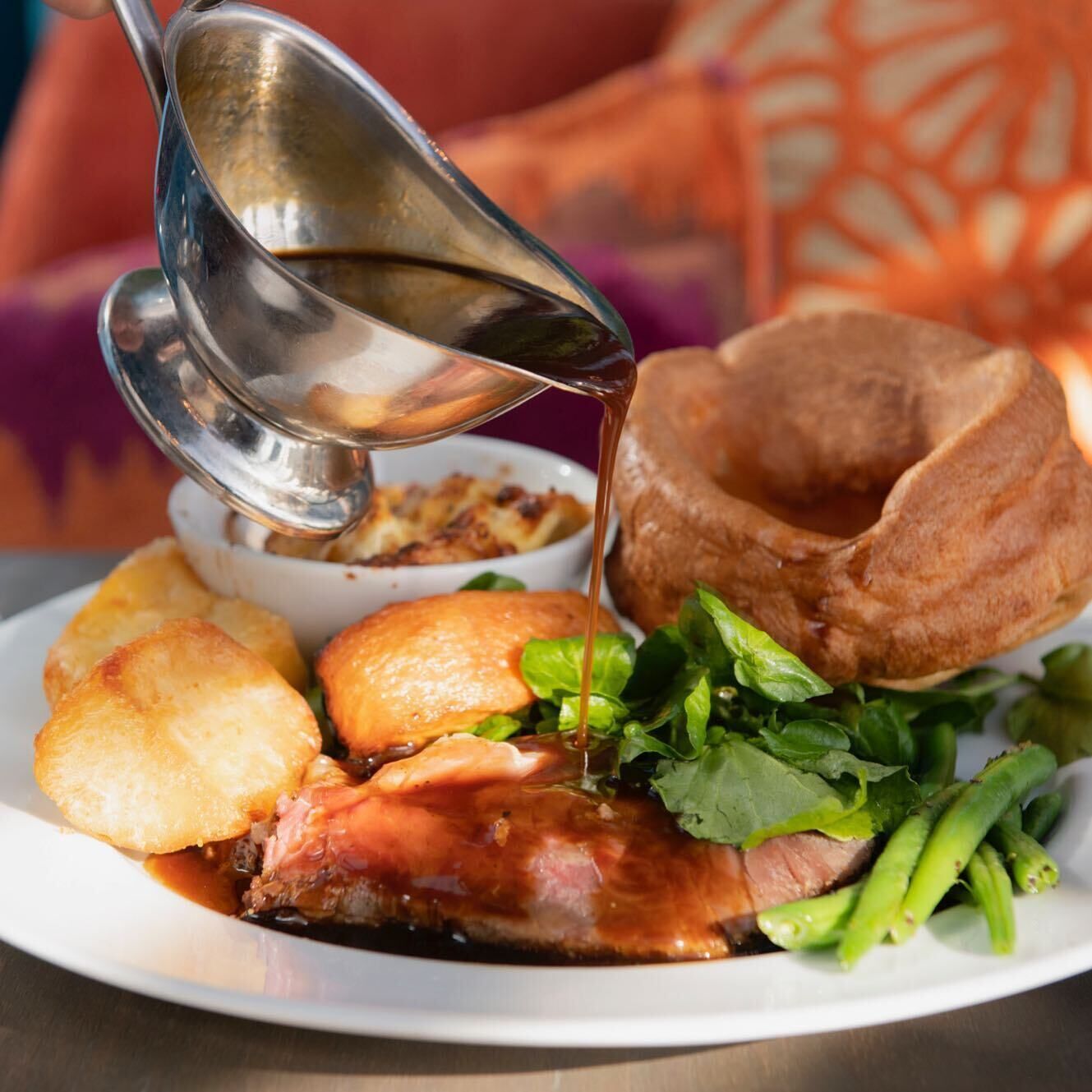 Une assiette comprenant un morceau de viande, un Yorkshire pudding et des légumes.