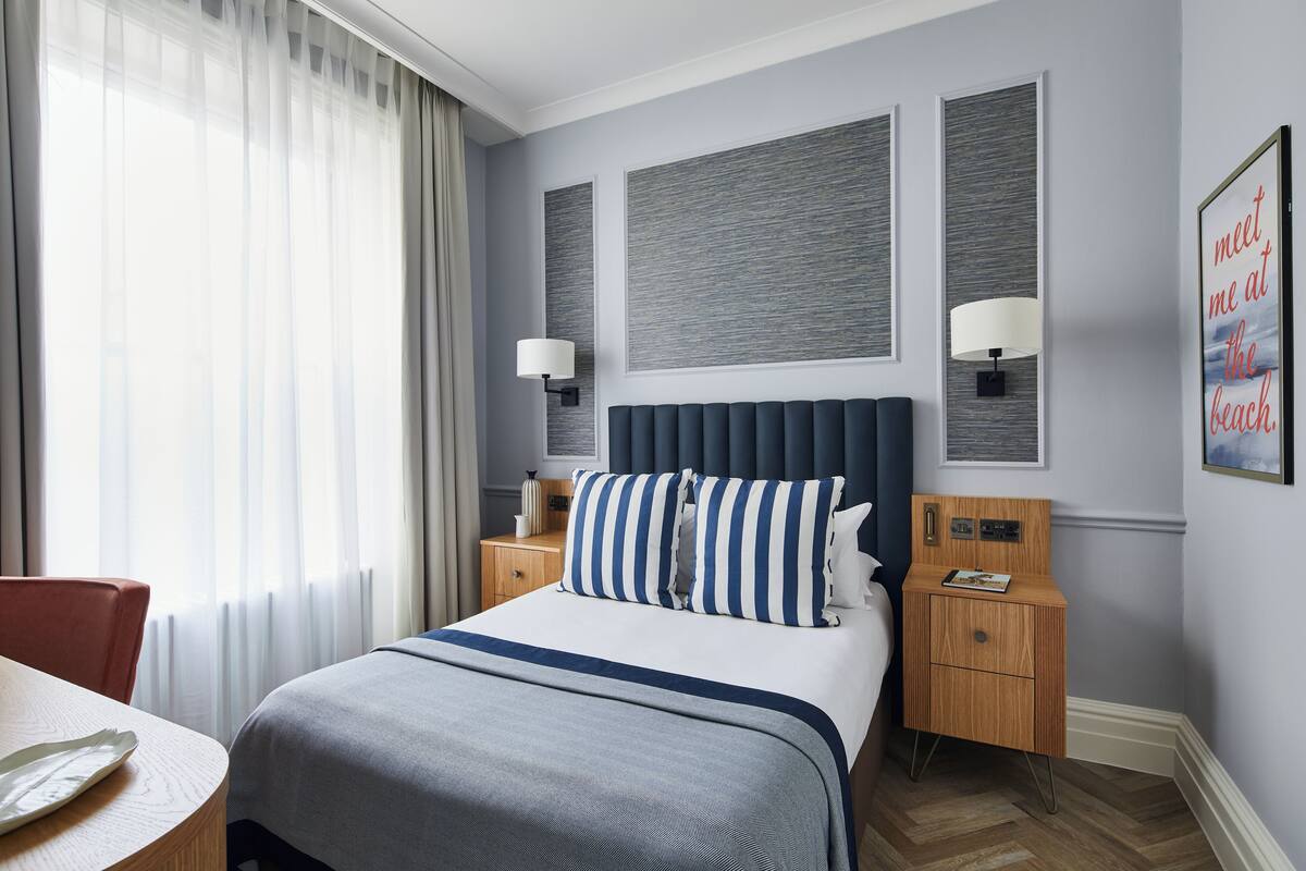 Une chambre d’hôtel avec un grand lit, deux tables de chevet, une petite table, un bureau et une chaise.