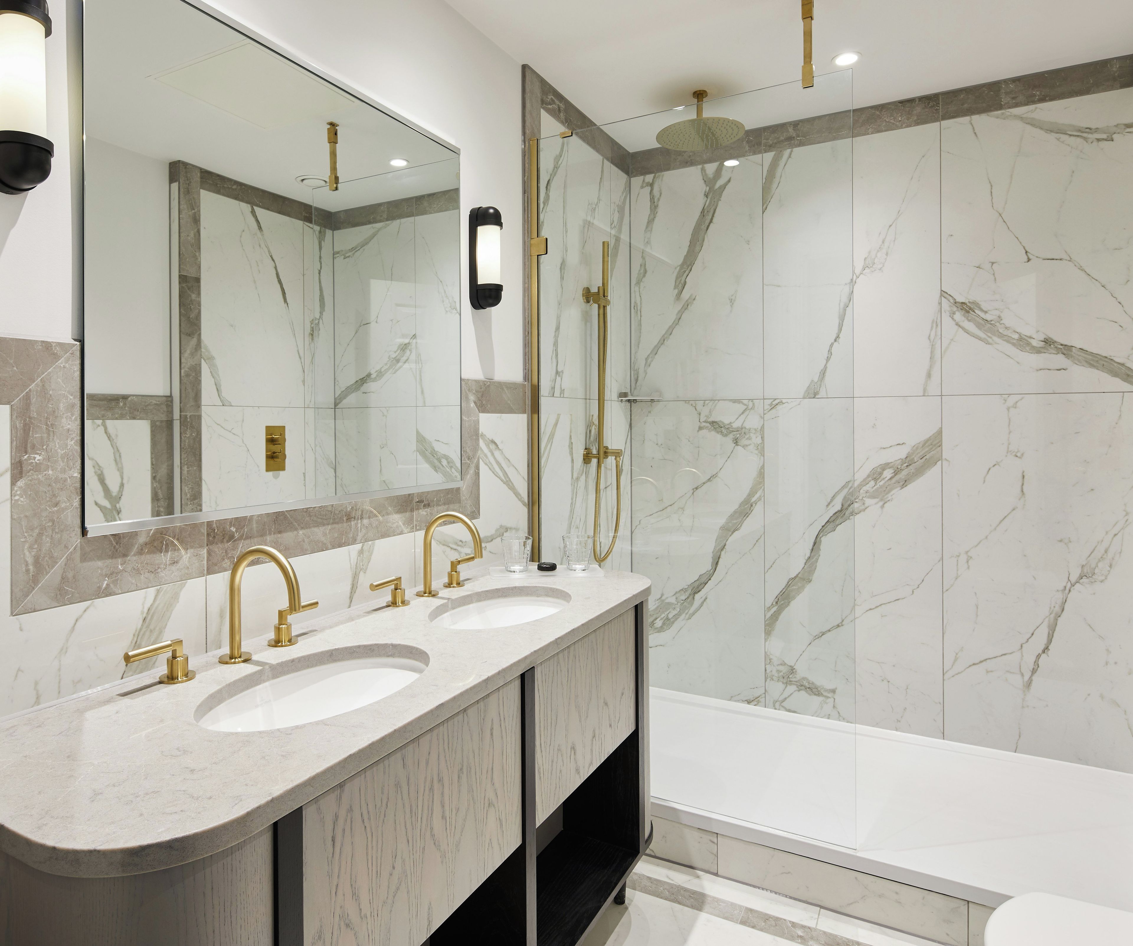 A modern bathroom with two sinks, a large mirror, and a shower area.