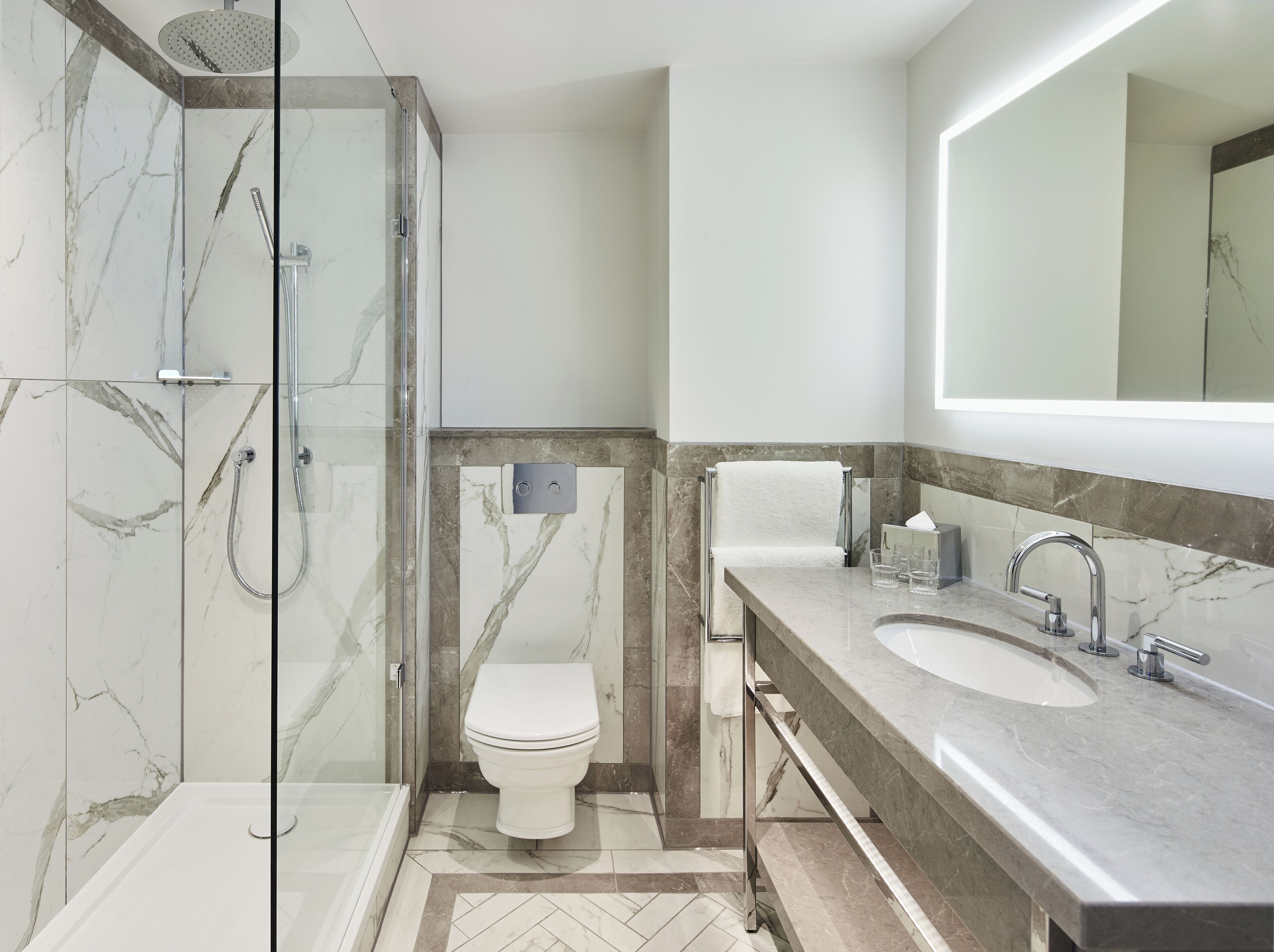 A modern bathroom with a glass-enclosed shower, a toilet, and a vanity with two sinks.