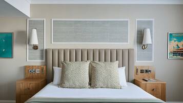 A hotel room with a large bed, two bedside tables, a headboard, and wall-mounted lamps.