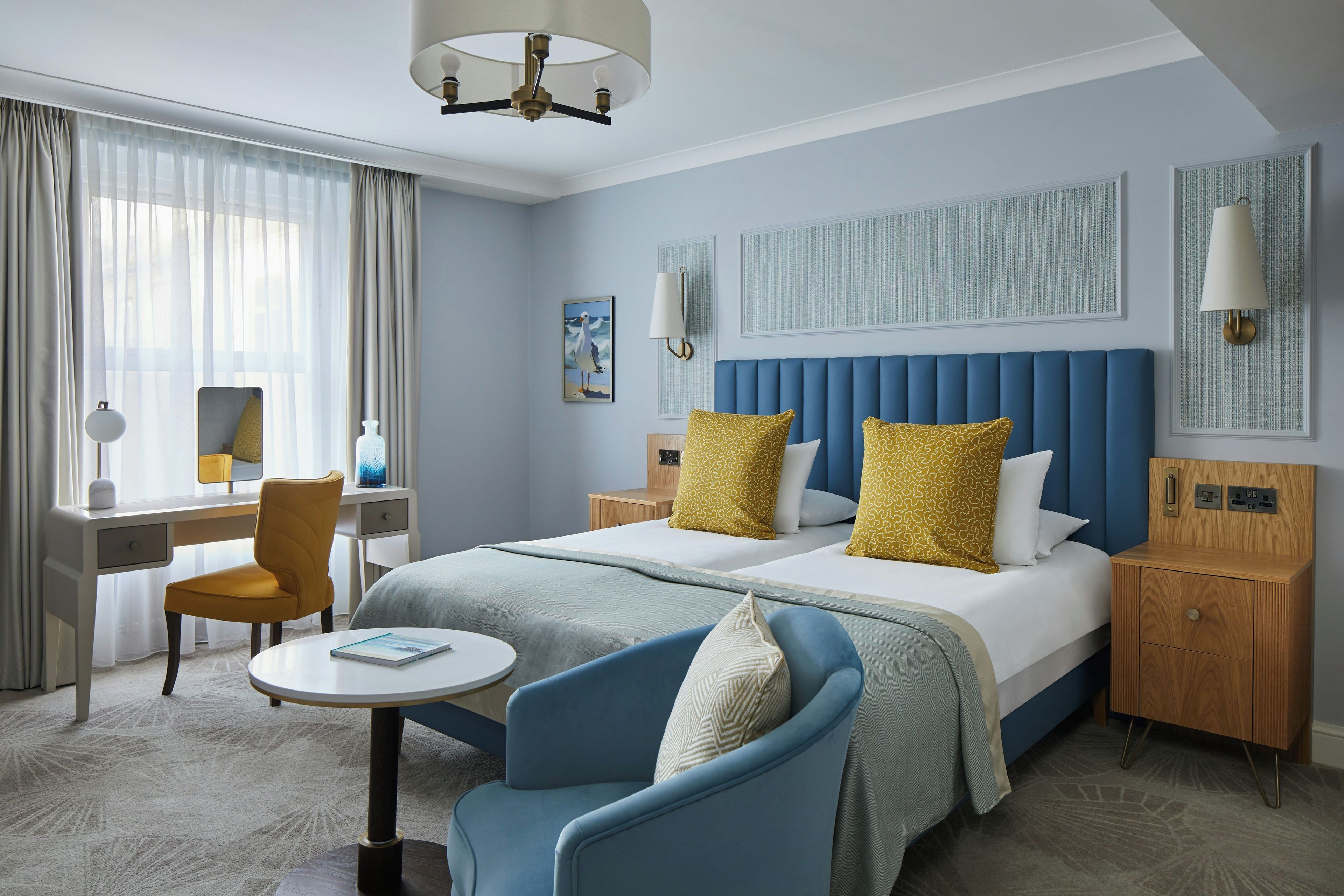 A hotel room with a large bed, a desk, a chair, a round table, and a nightstand.
