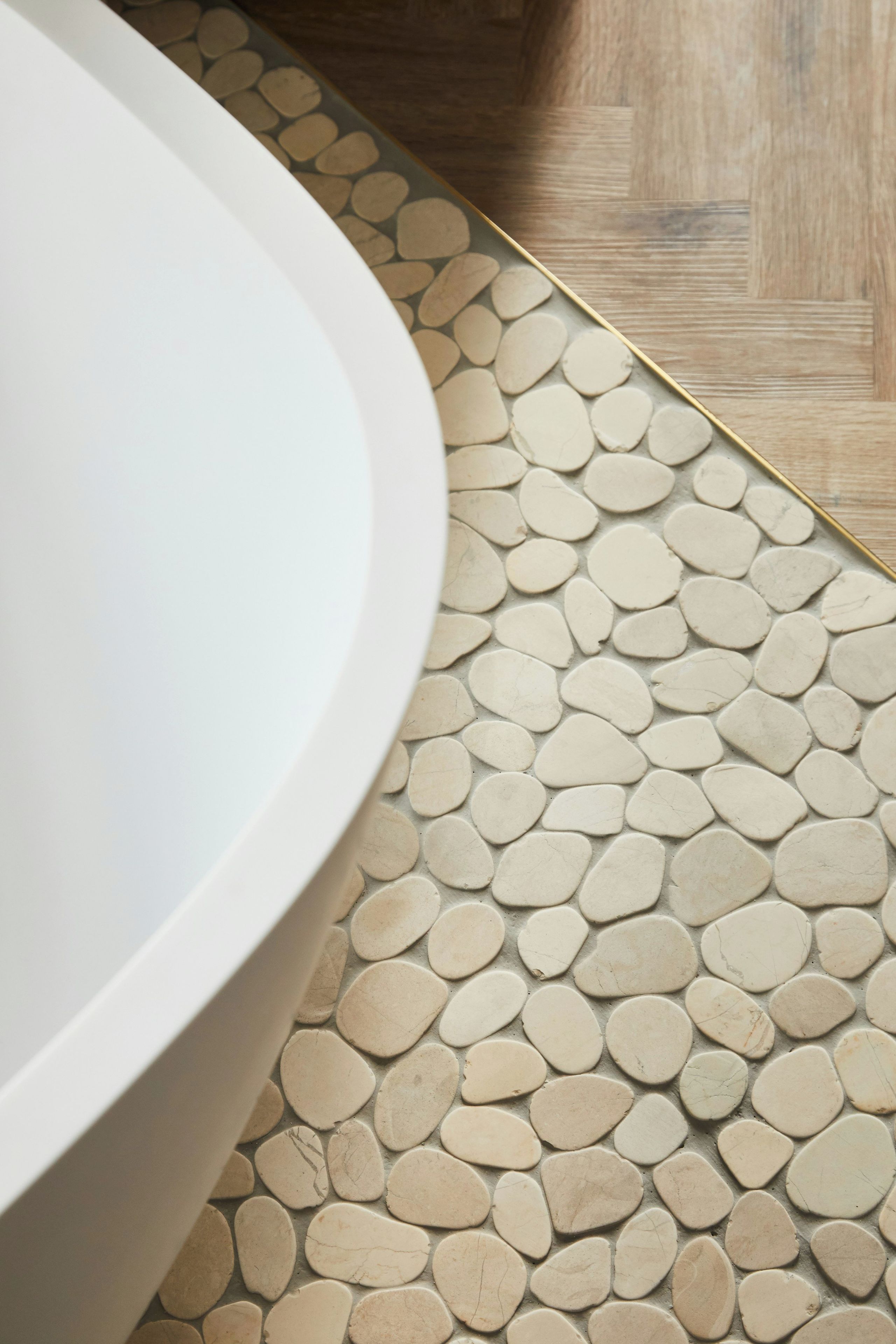 Une salle de bain avec une baignoire blanche et un revêtement de sol imitant des galets.