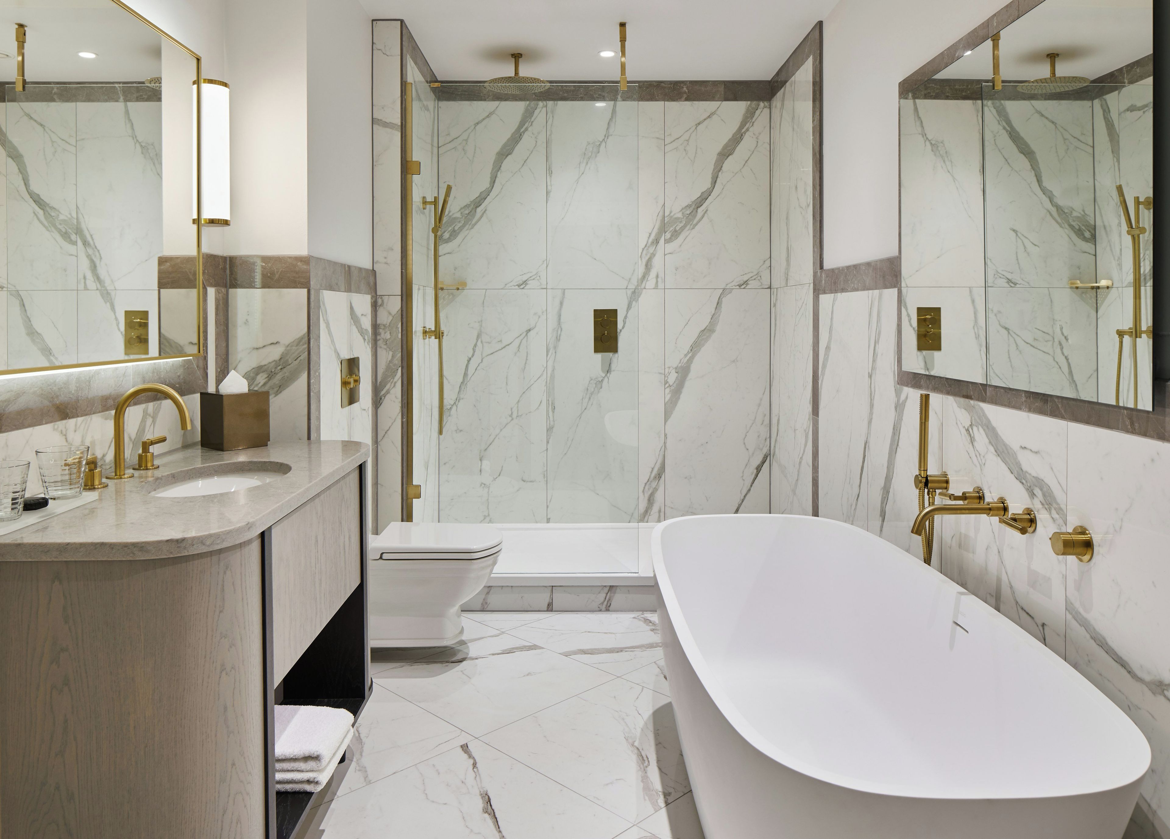 Une salle de bain moderne avec une baignoire sur pieds, une douche à parois de verre et un meuble-lavabo doté d'un robinet doré.