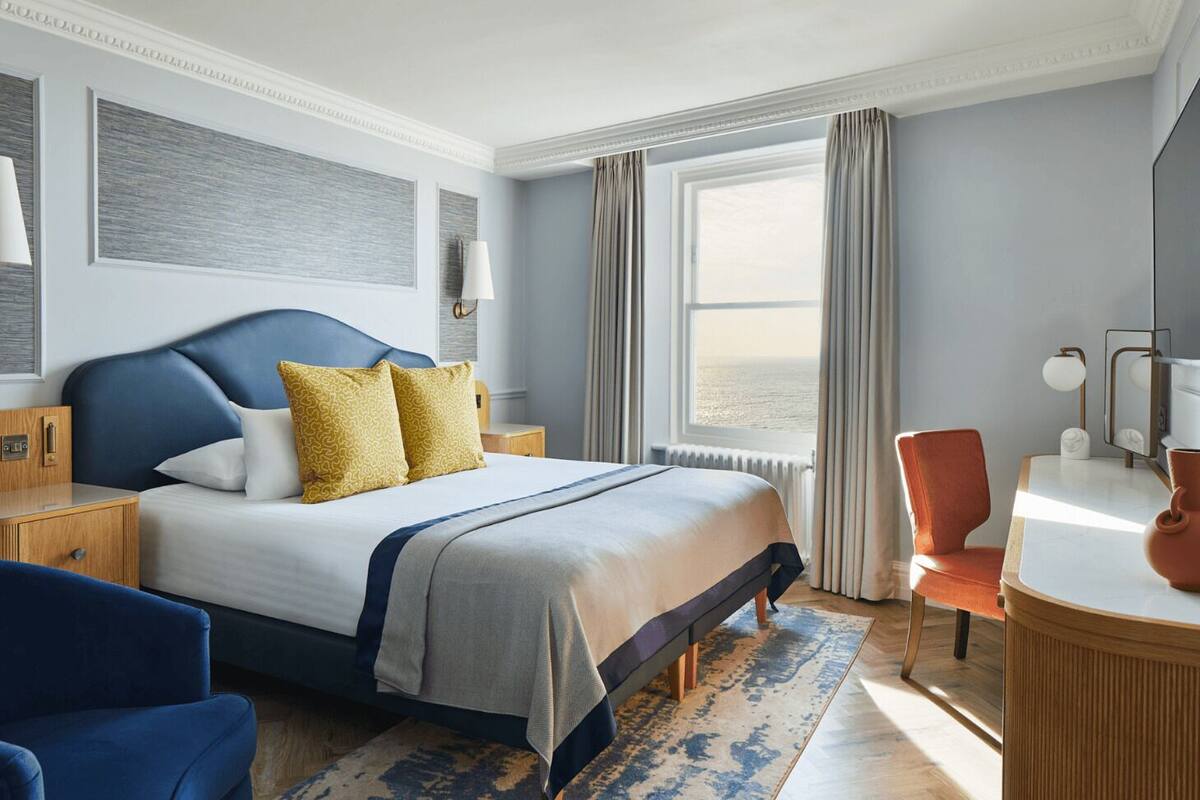 Une chambre d’hôtel moderne dotée d’un grand lit, d’un bureau et offrant une vue sur la mer.
