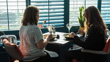 Dos personas cenando en una mesa con vistas al exterior a través de amplios ventanales.