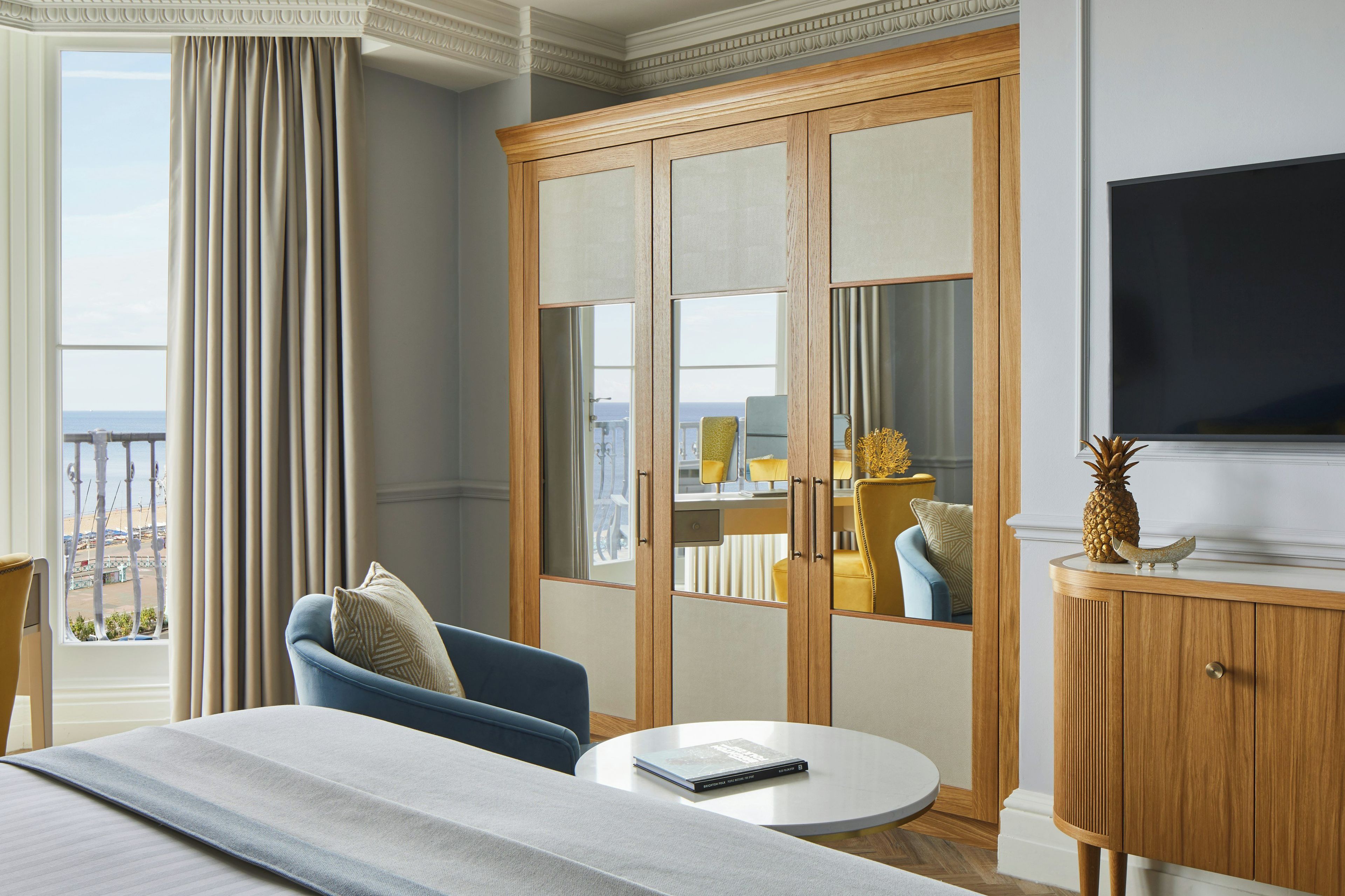 Habitación de hotel con cama, una mesa redonda, televisión, armario y vistas al mar.