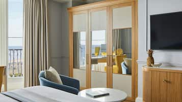 Habitación de hotel con cama, una mesa redonda, televisión, armario y vistas al mar.