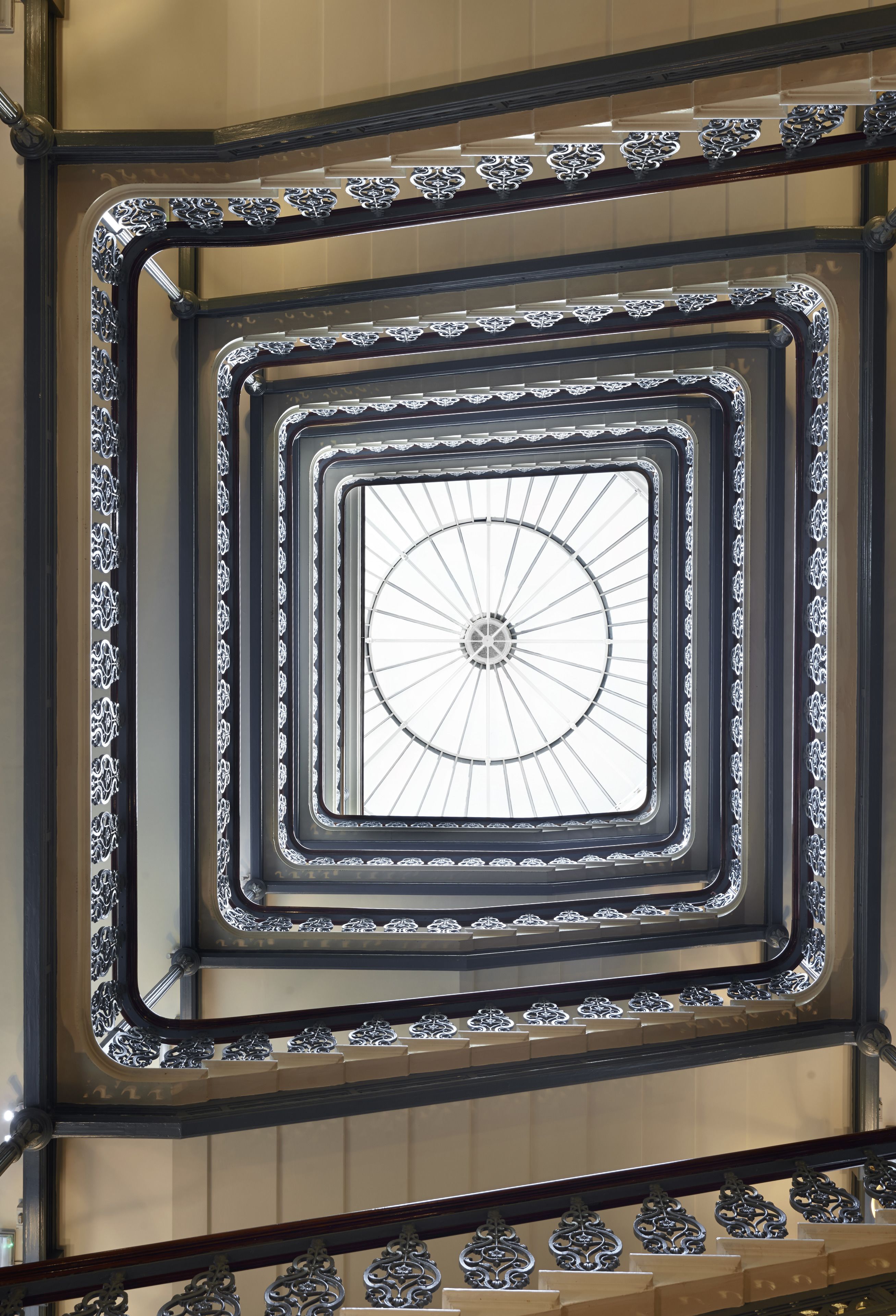 A spiral staircase with ornate metal railings and a central glass window.