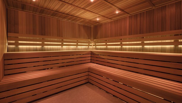 Un sauna avec des bancs en bois et un plafond incliné.