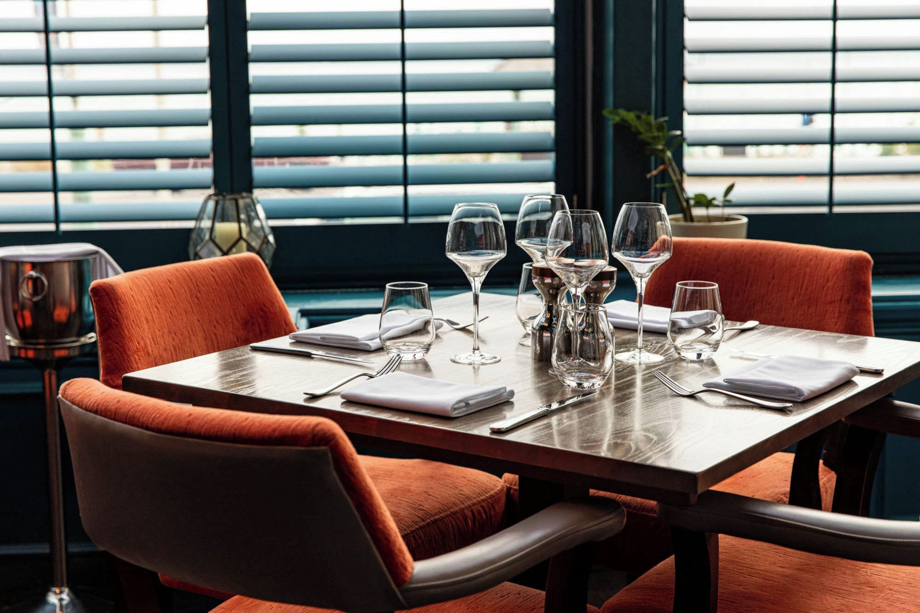 Une table à manger dressée pour six personnes, avec des chaises, une bougie et un ensemble salière et poivrière.