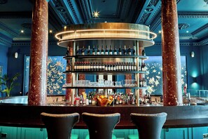 A bar area with a multi-tiered shelving unit displaying bottles, glasses, and a fruit bowl.