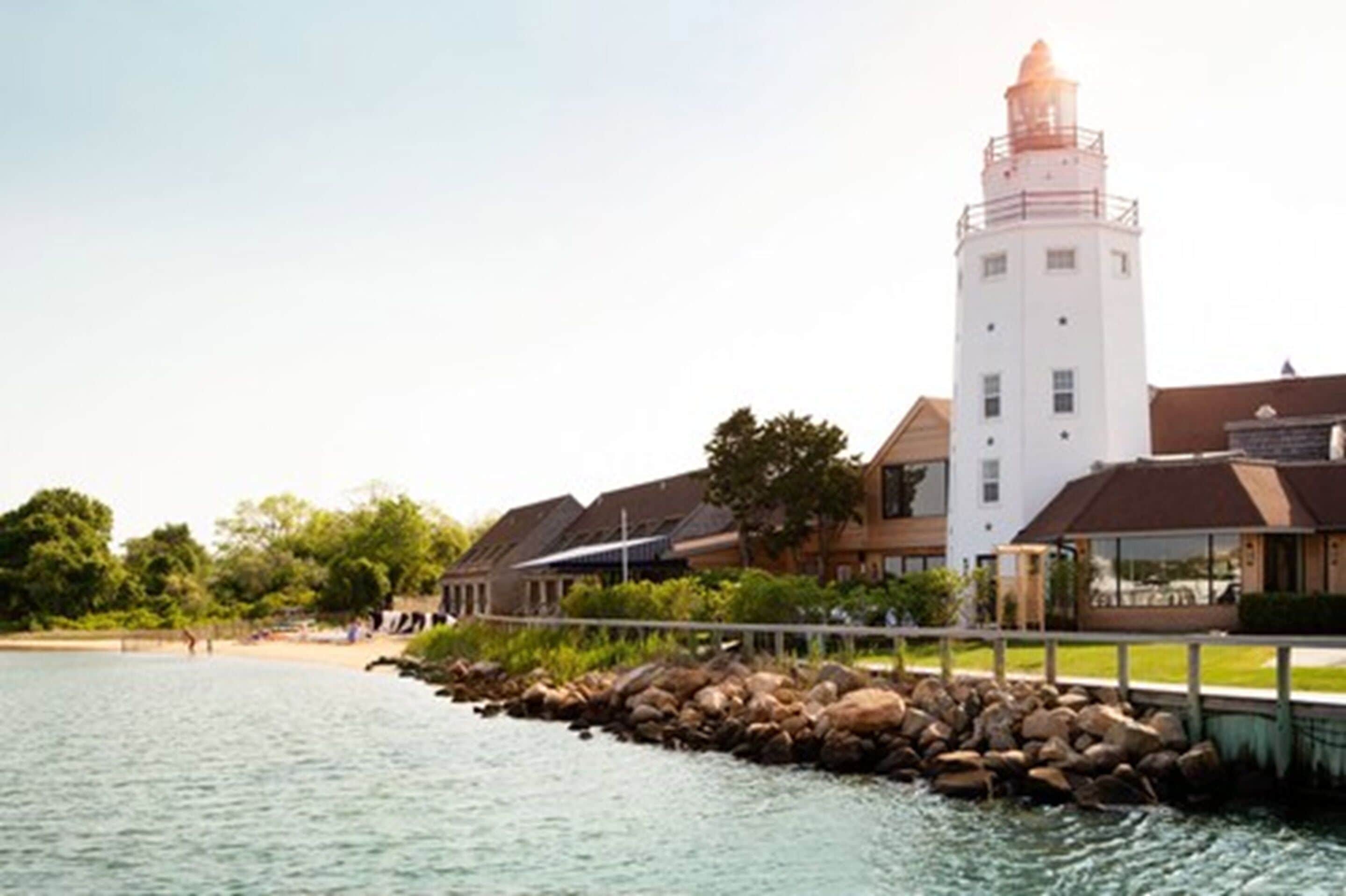 A coastal building with a lighthouse, a pier, and a beach.