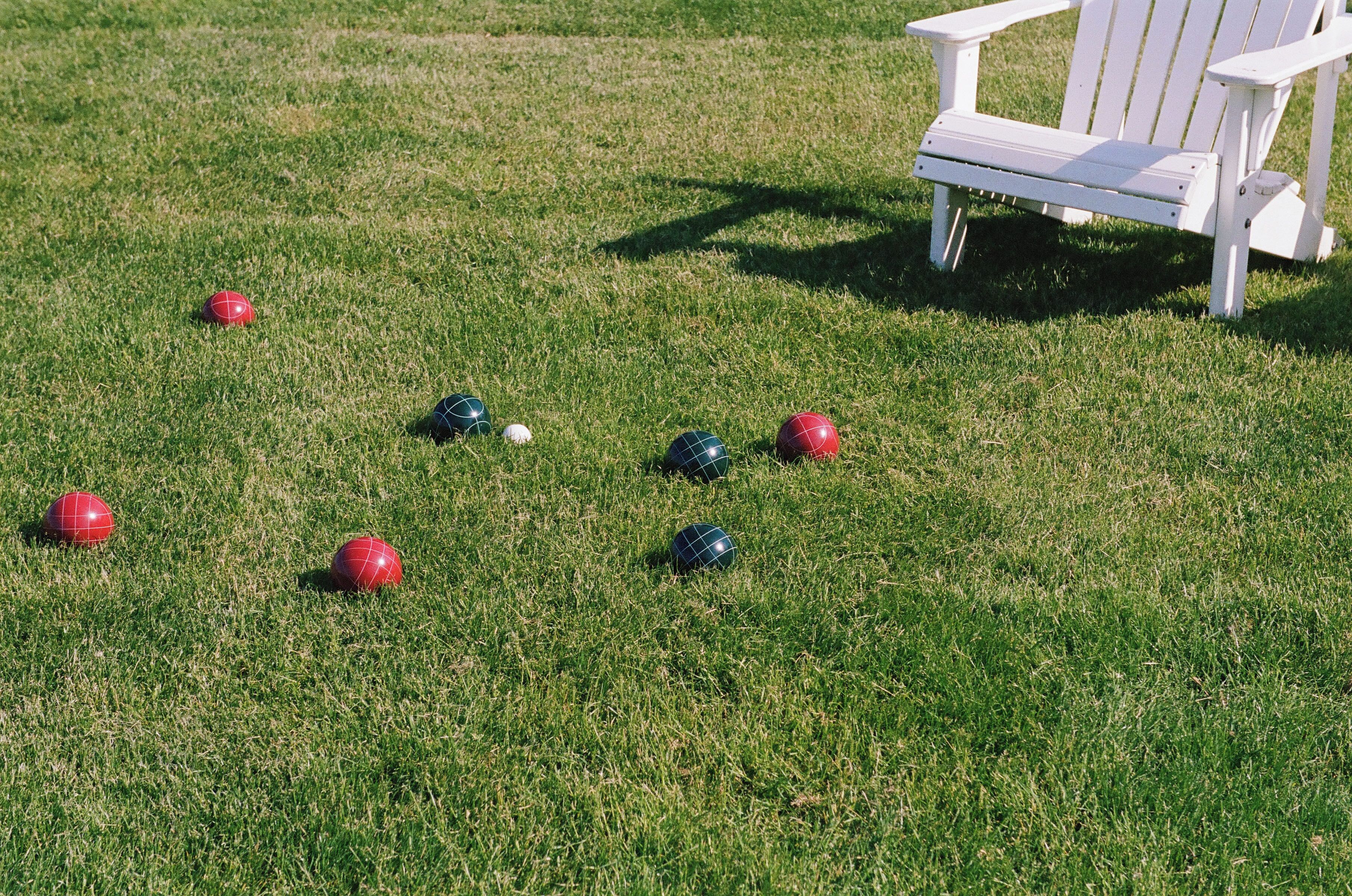 A lawn with croquet balls and a white chair.