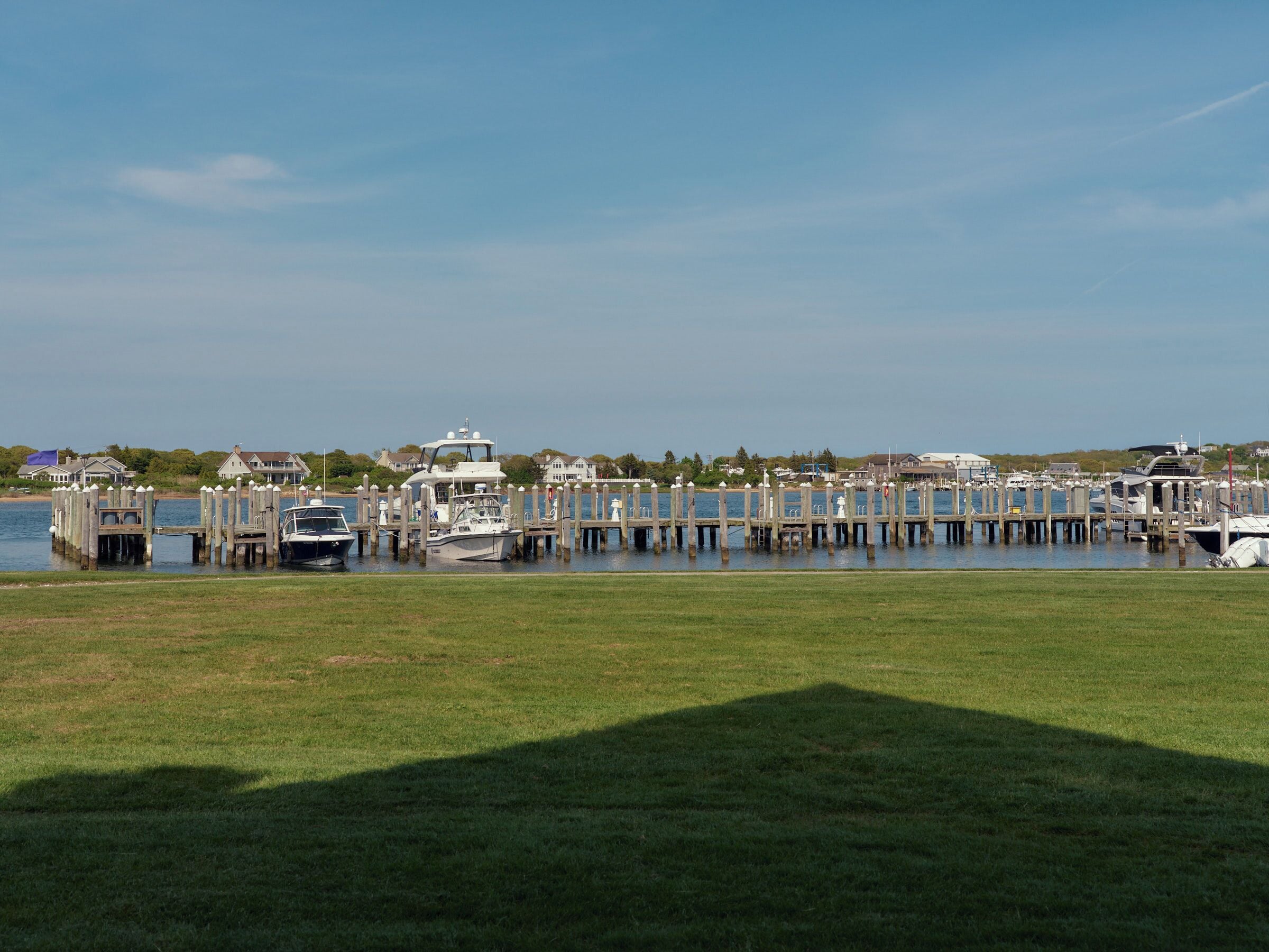 A marina with docked boats and a grassy area in the foreground.