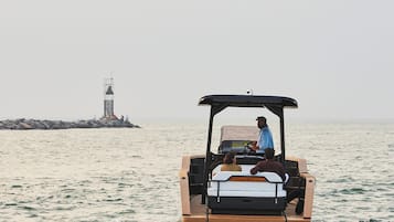 A golf cart on water with a lighthouse in the background.