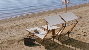 Une plage avec deux chaises longues, un parasol et un panier.