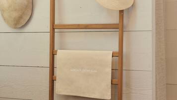 Una escalera de madera con una toalla color crema y un sombrero de paja colgados.