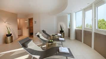Un área de spa moderna con sillones reclinables, plantas en macetas y vistas al exterior a través de grandes ventanales.