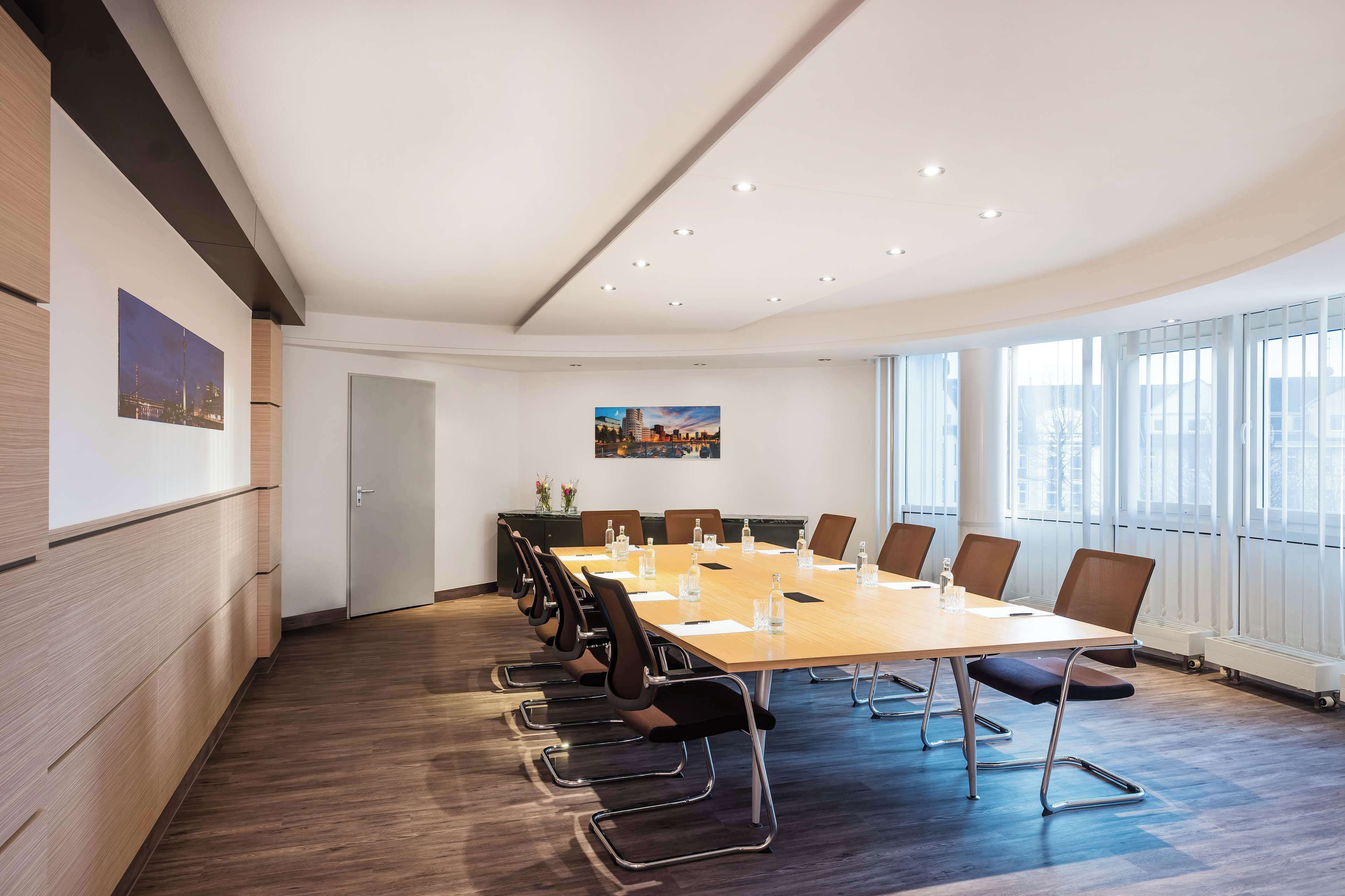 A conference room with a long table, chairs, and a whiteboard.