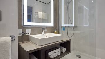 Un baño moderno con un espejo grande, un lavabo, una ducha y un perchero para toallas.