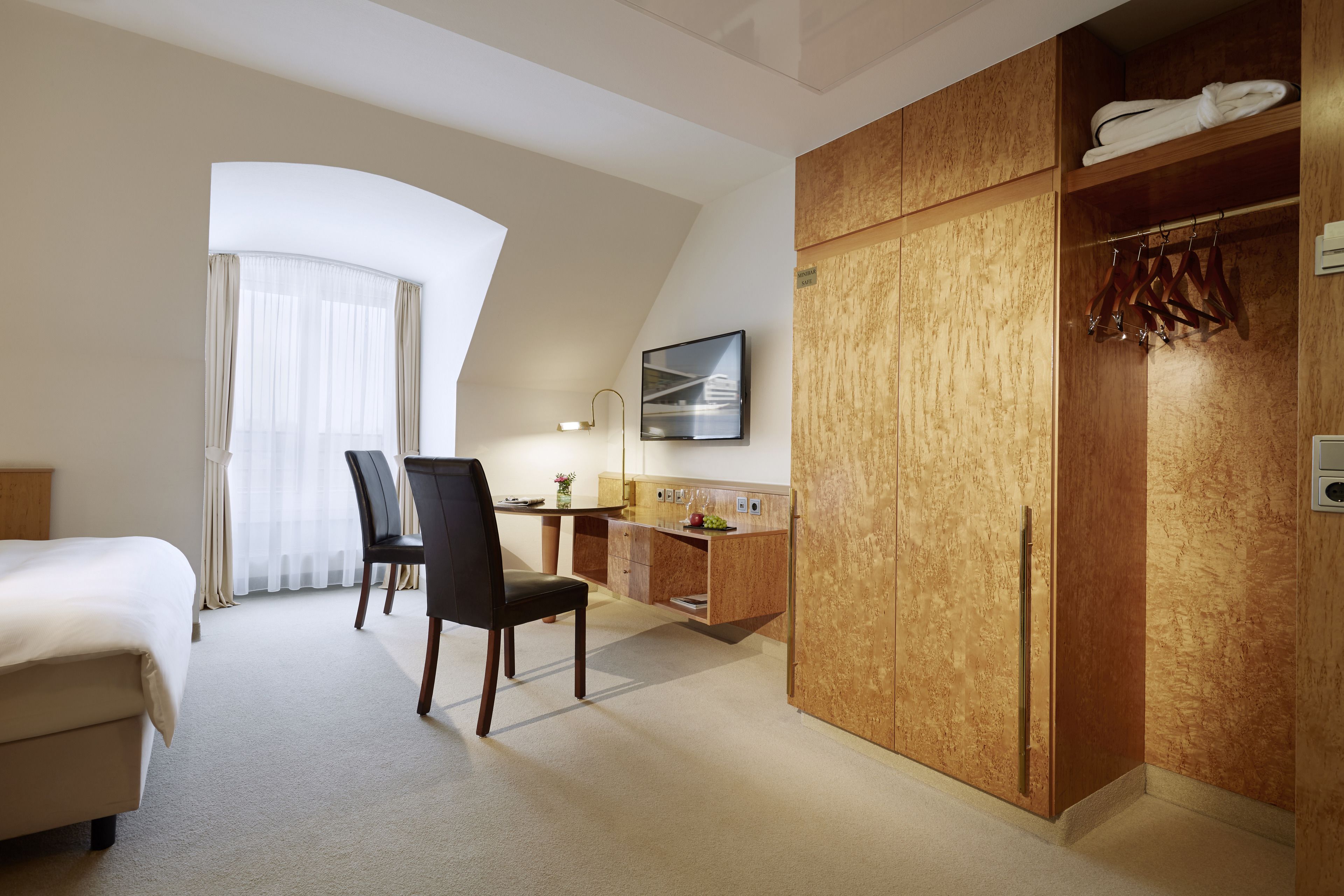 Habitación de hotel con cama, escritorio, silla y armario.