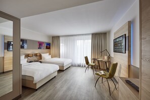 A hotel room with two beds, a desk with a chair, a TV, and a window with curtains. - Lindner Hotel Dusseldorf Airport, part of JdV by Hyatt (Düsseldorf)