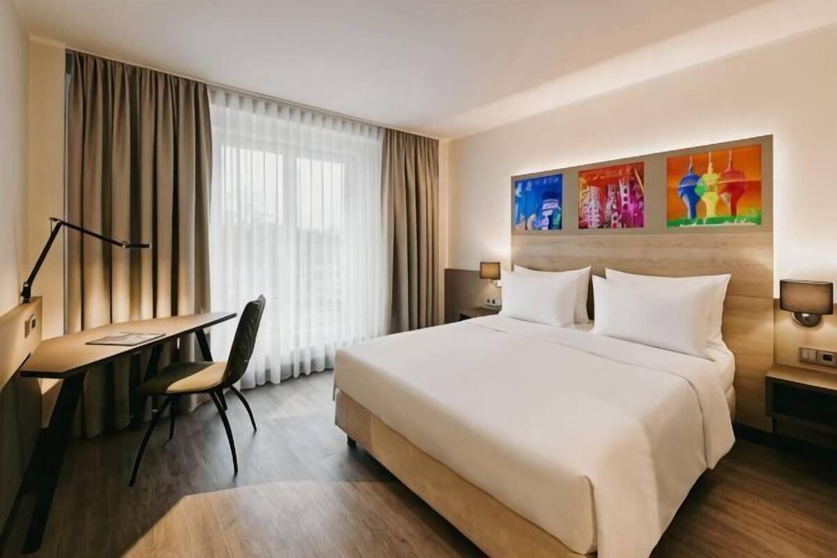Une chambre d’hôtel avec un lit, un bureau, une chaise et une œuvre d’art au mur.