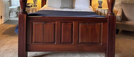 A four-poster bed with a wooden frame, white bedding, and two bedside lamps.