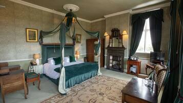 A four-poster bed with a canopy, a fireplace, a television, and a desk with a chair.